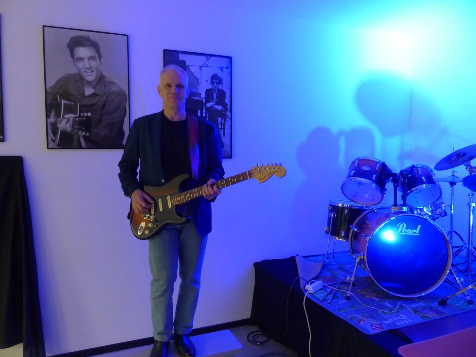 Volker Waldau mit Fender Stratocaster in unserem Bandraum, dahinter ein Schlagzeug