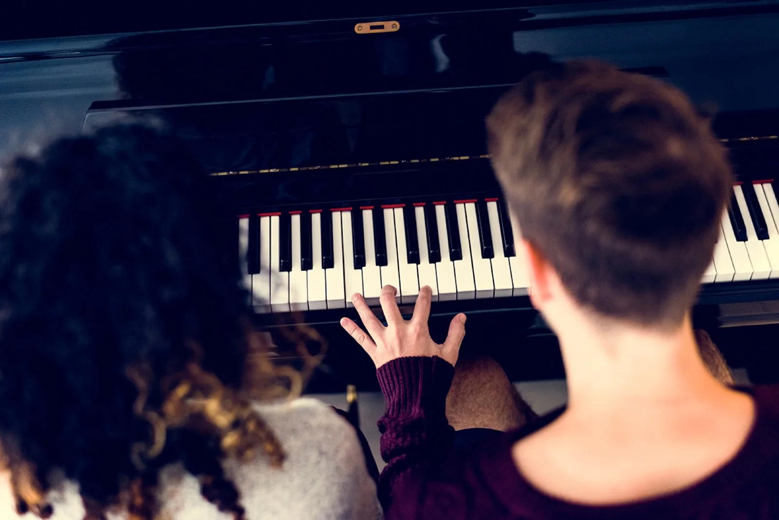 Zwei Menschen üben gemeinsam am Klavier